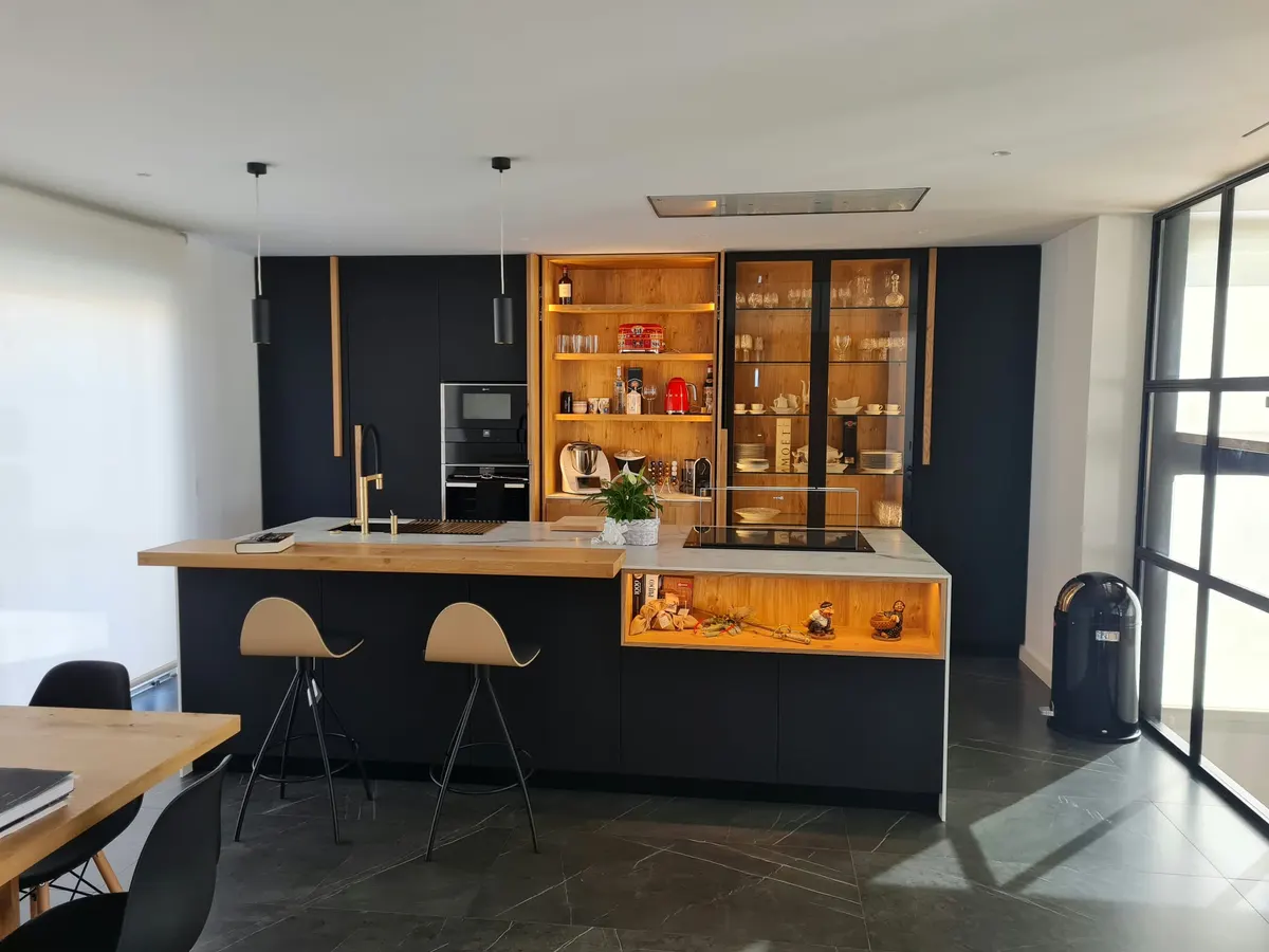 Cocina negra abierta al salón con isla iluminada